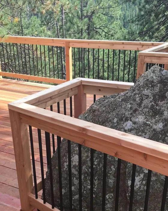 Cedar deck railing framed around a large granite boulder
