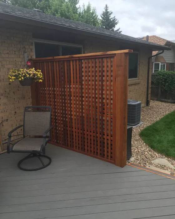 Stained wood privacy screen with lattice top on a gray deck