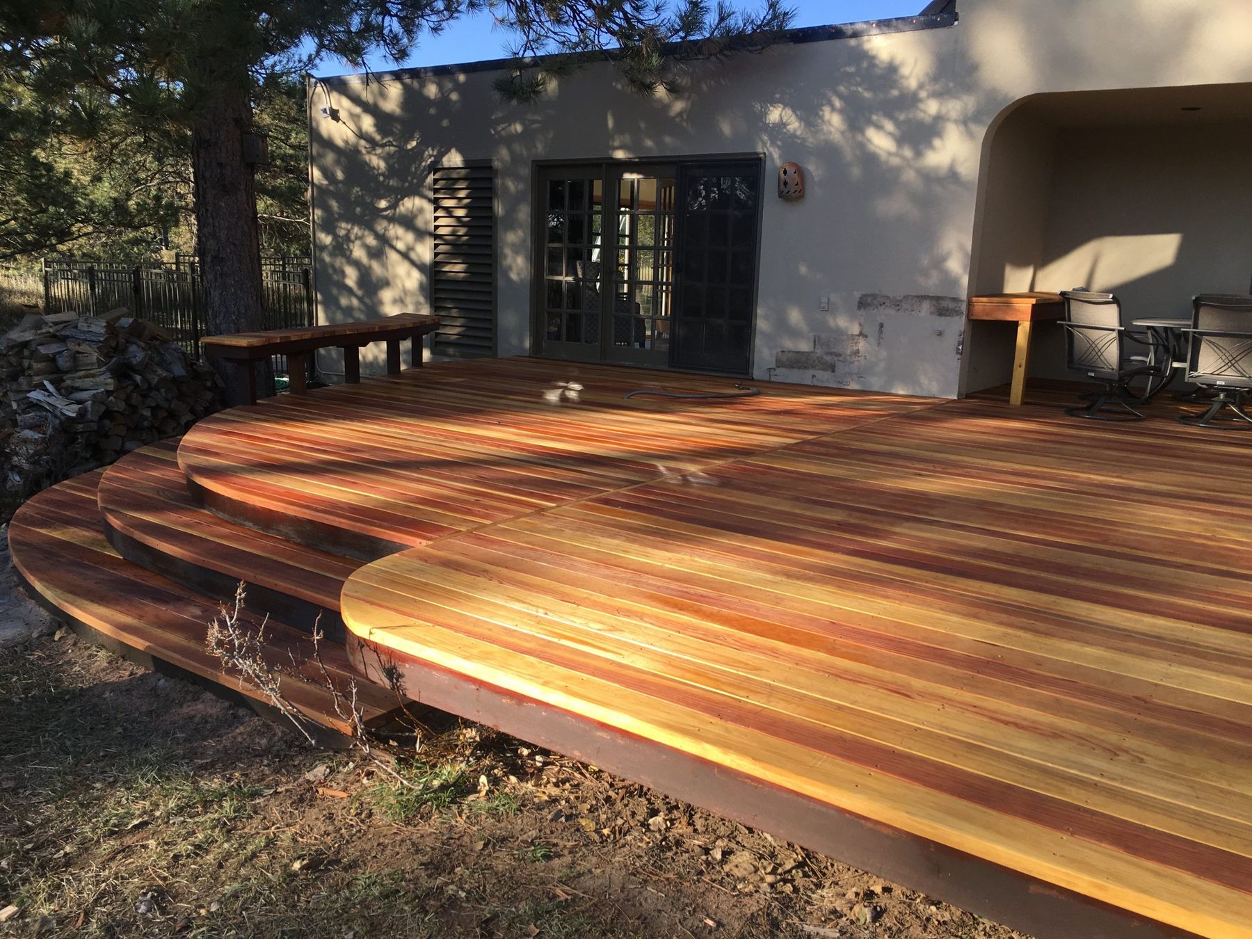 Rebuilt deck in Genesee with three curved steps and new benches, the boards glowing in late afternoon sun