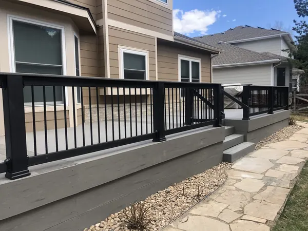 Samuels deck after: new gray deck with black railings and steps to a flagstone path