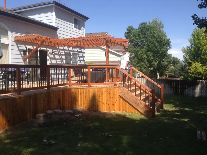New raised deck with stairs, cedar skirting and a large pergola above
