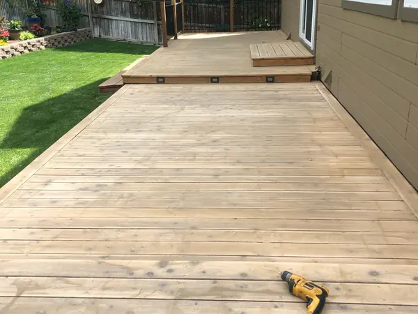 Swankee deck before: long ground-level deck with pale, weathered boards